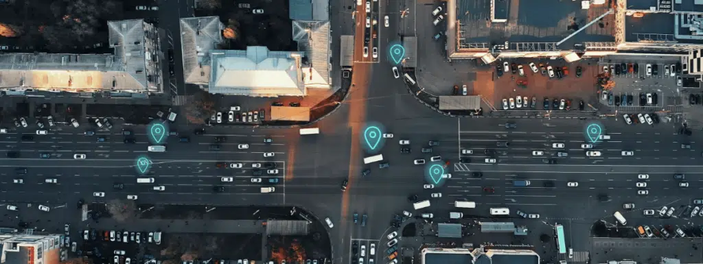 aerial view of city intersection with many cars and gps navigation system symbols. autonomous driverless vehicles in city traffic. future transportation concept min